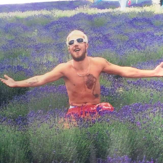 man squatting amongst flowers with arms outstretched