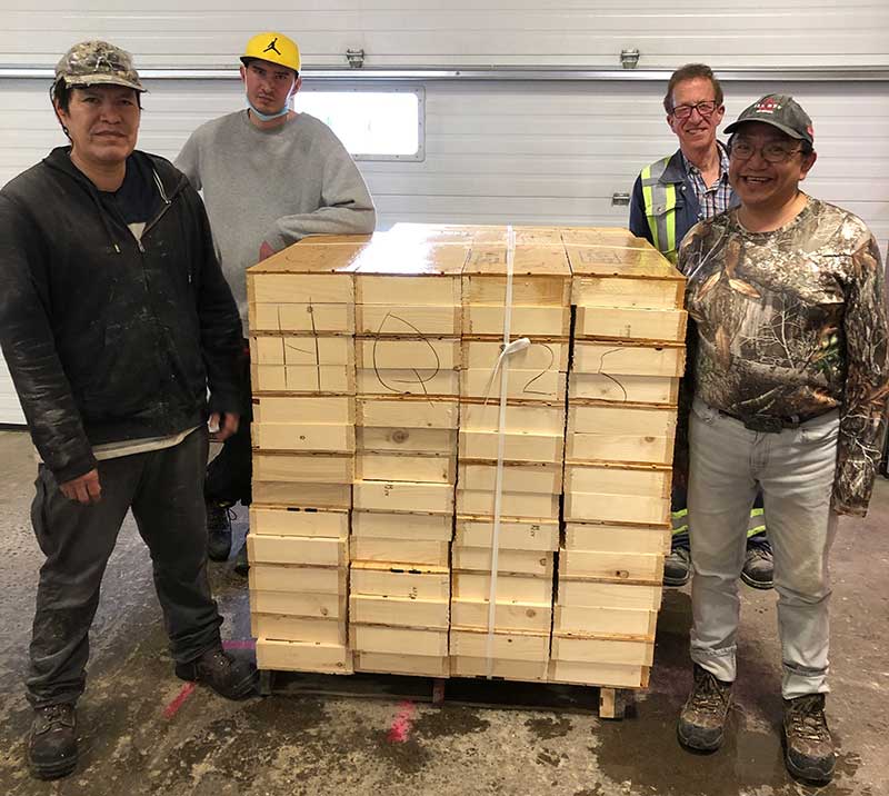 Four workers standing near completed stack of core boxes